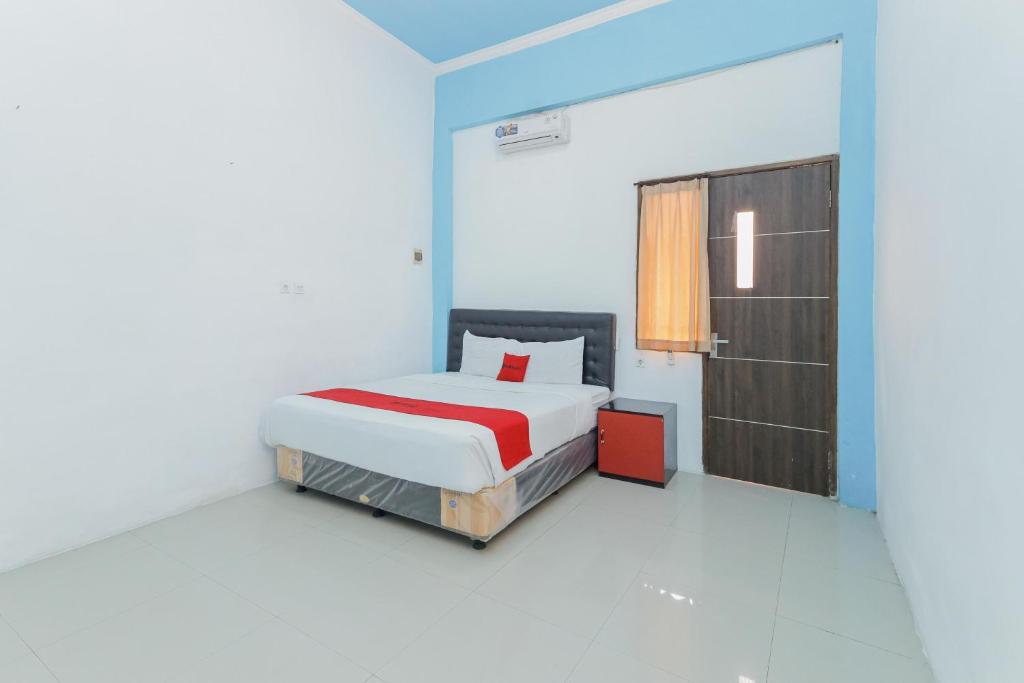 a bedroom with a bed and a door in it at RedDoorz at Bypass Town Square Mojokerto in Mojokerto