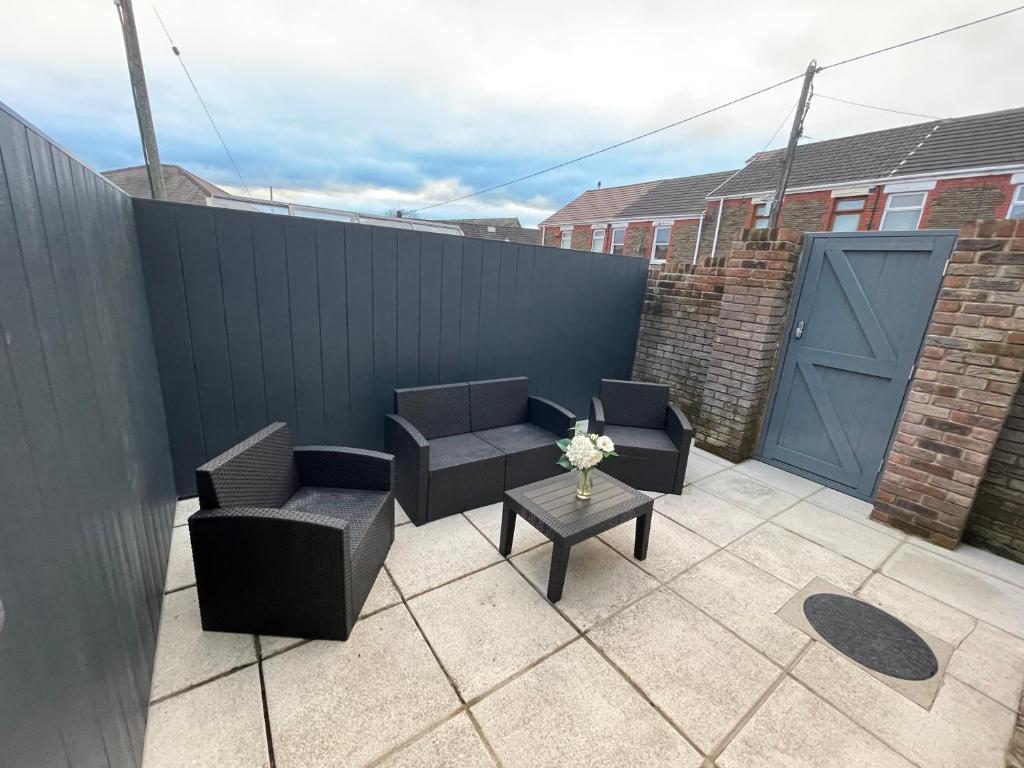 a patio with two chairs and a table and a fence at Hyfrydol Bach in Maesteg