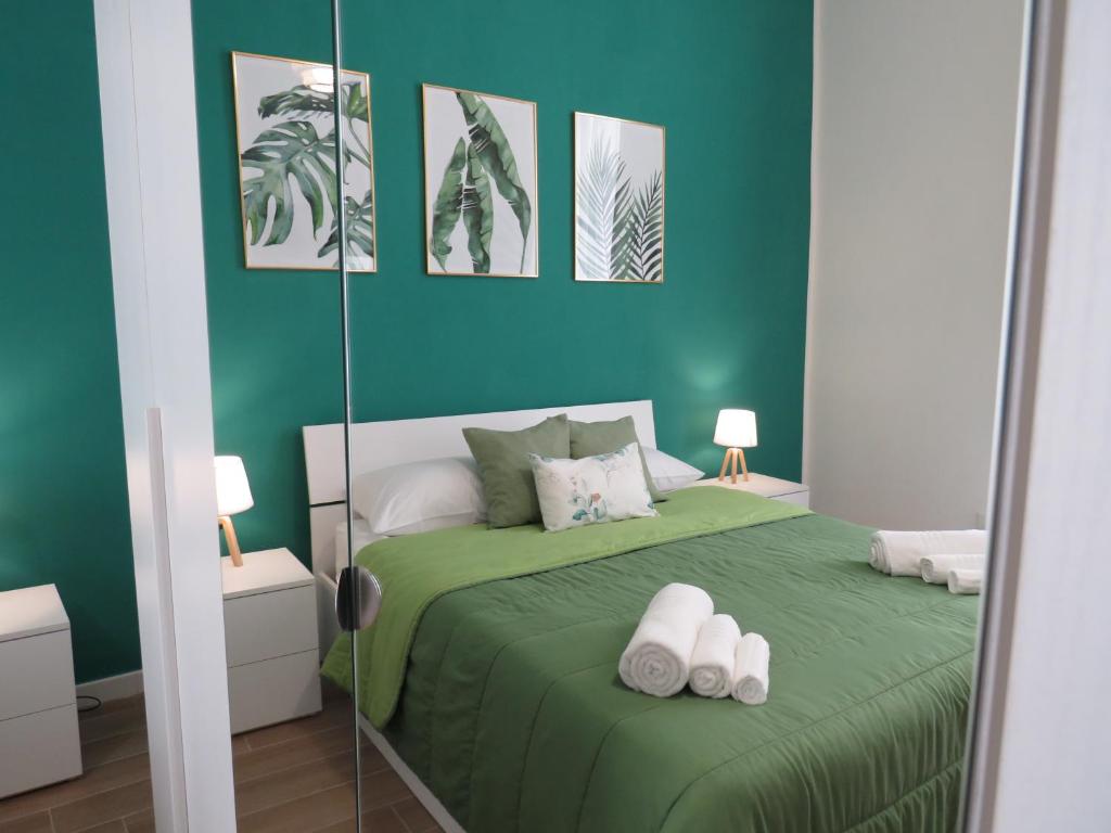1 dormitorio verde con 1 cama y 2 toallas blancas en TRISOLE Palermo en Palermo