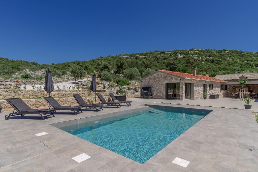 einen Pool mit Stühlen und ein Haus in der Unterkunft Private Villa Bosilen Marina by Trogir Split airport Sibenik in Marina