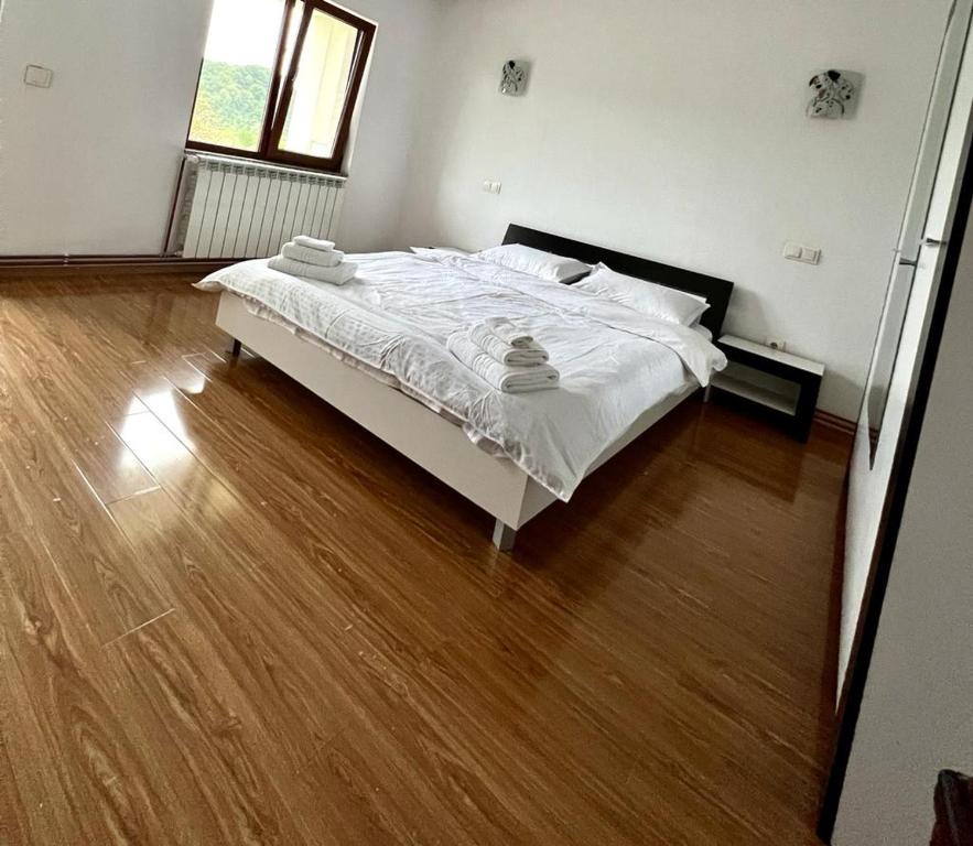 a bedroom with a white bed and a wooden floor at Casa Rus in Leordina