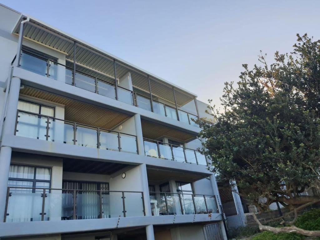 un edificio de apartamentos con balcones y un árbol en Coogee Bay Apartments, en Gonubie