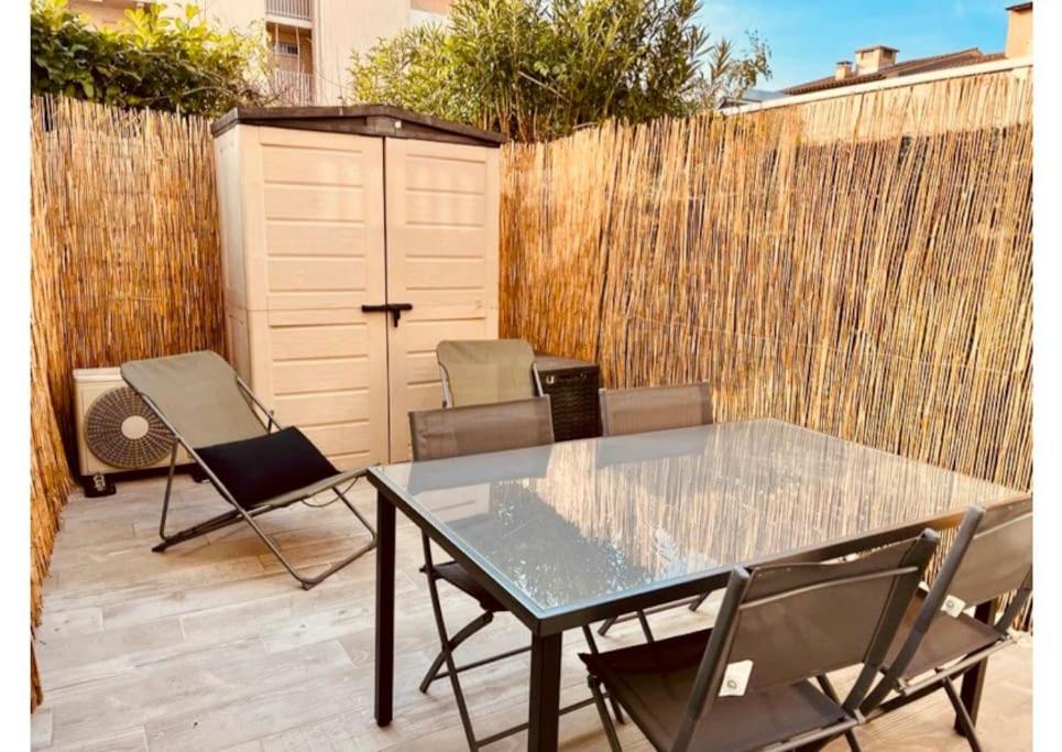 um pátio com uma mesa e cadeiras de vidro e uma cerca em Logement rénové en résidence, climatisé, terrasse em Sanary-sur-Mer