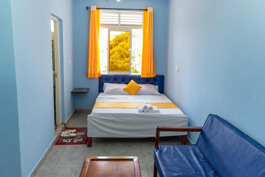 ein blaues Schlafzimmer mit einem Bett und einem Fenster in der Unterkunft Inkaba Resort & Conference Centre Kilifi in Kilifi