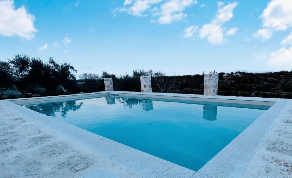 une grande piscine d'eau bleue dans l'établissement TRULLO PIETRAPOESIA, à Ostuni