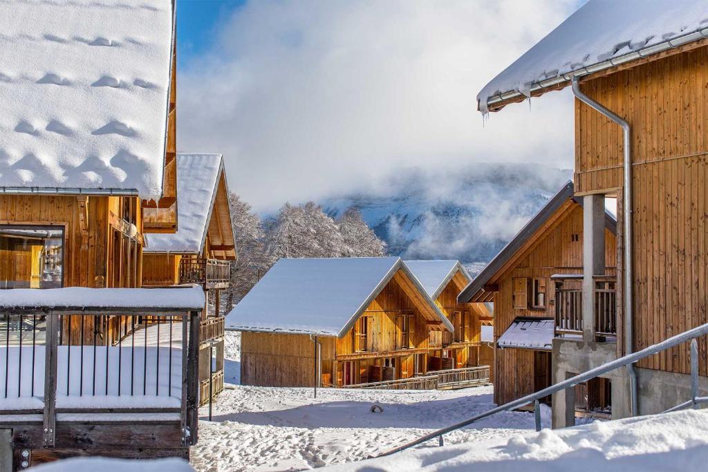 un grupo de edificios de madera en la nieve en Madame Vacances Les Chalets Du Berger, en La Féclaz