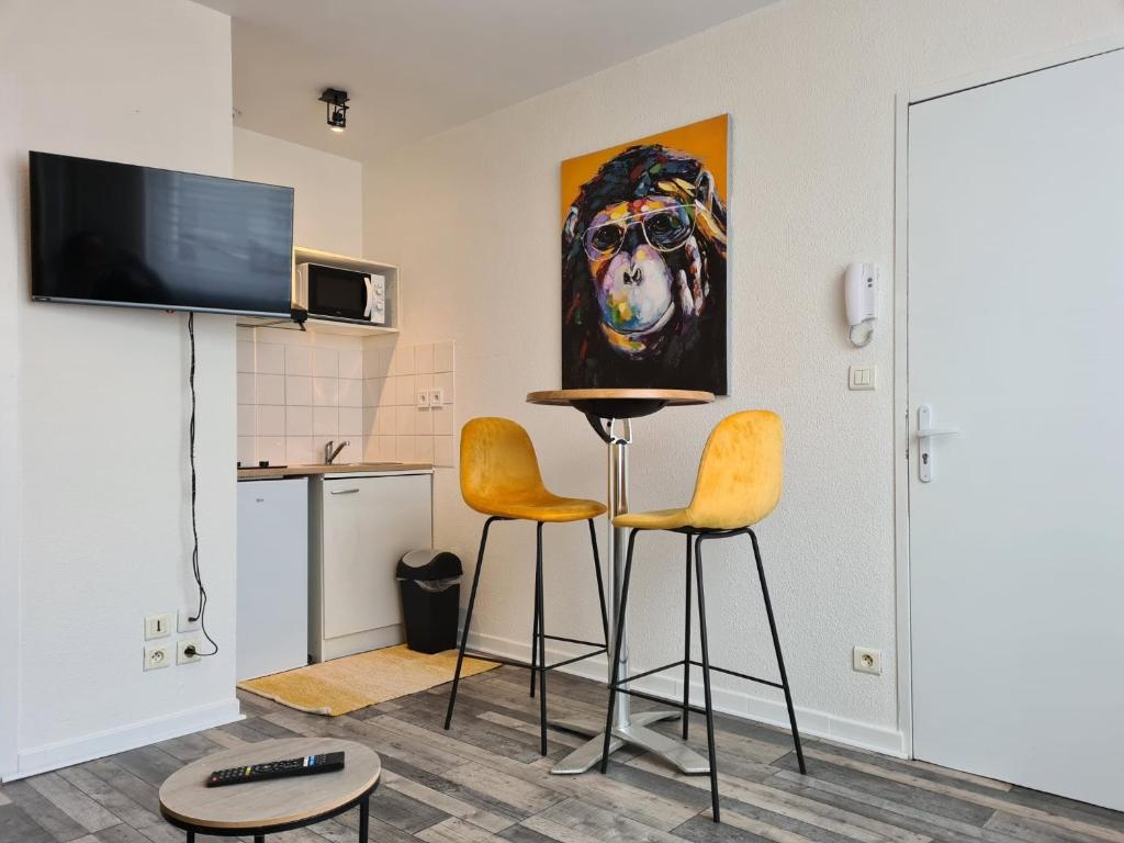 ein Wohnzimmer mit 2 Stühlen und einem Gemälde eines Hundes in der Unterkunft studio d'henri in Agen