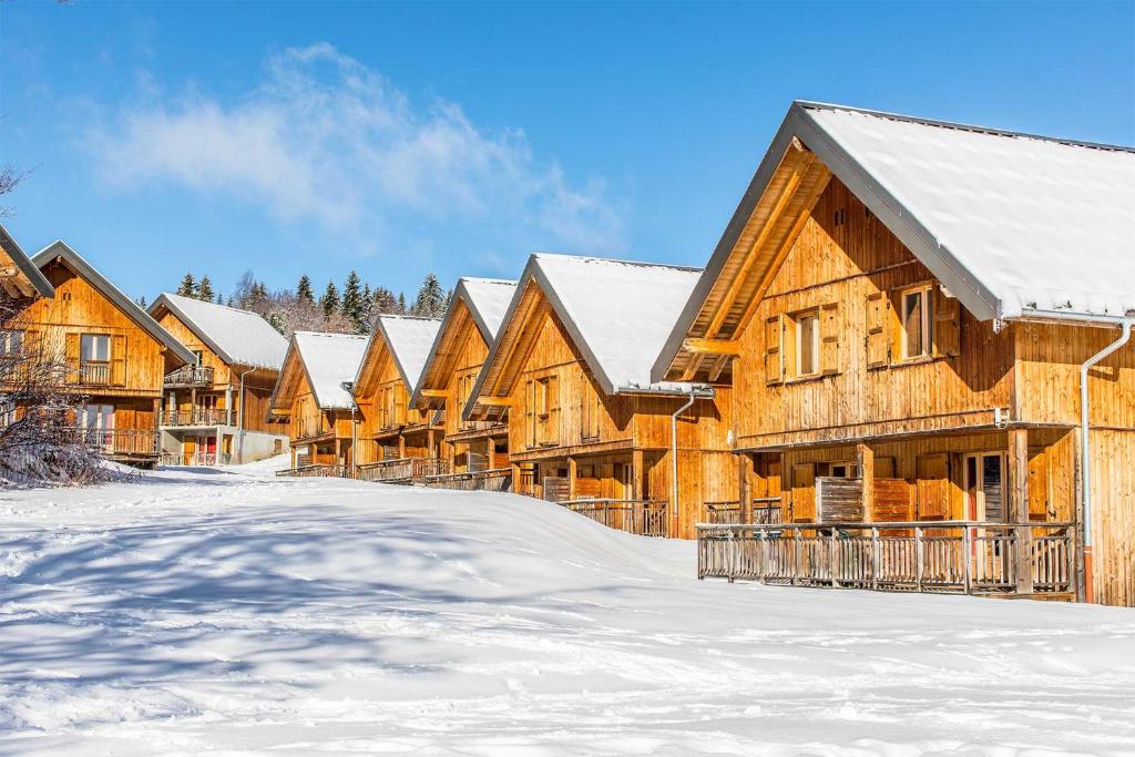 a row of wooden houses in the snow at Madame Vacances Les Chalets Du Berger in La Féclaz