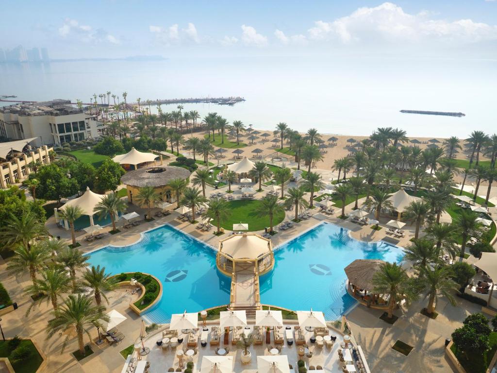 InterContinental Doha Beach & Spa, an IHG Hotel في الدوحة: اطلالة جوية على منتجع فيه مسبحين