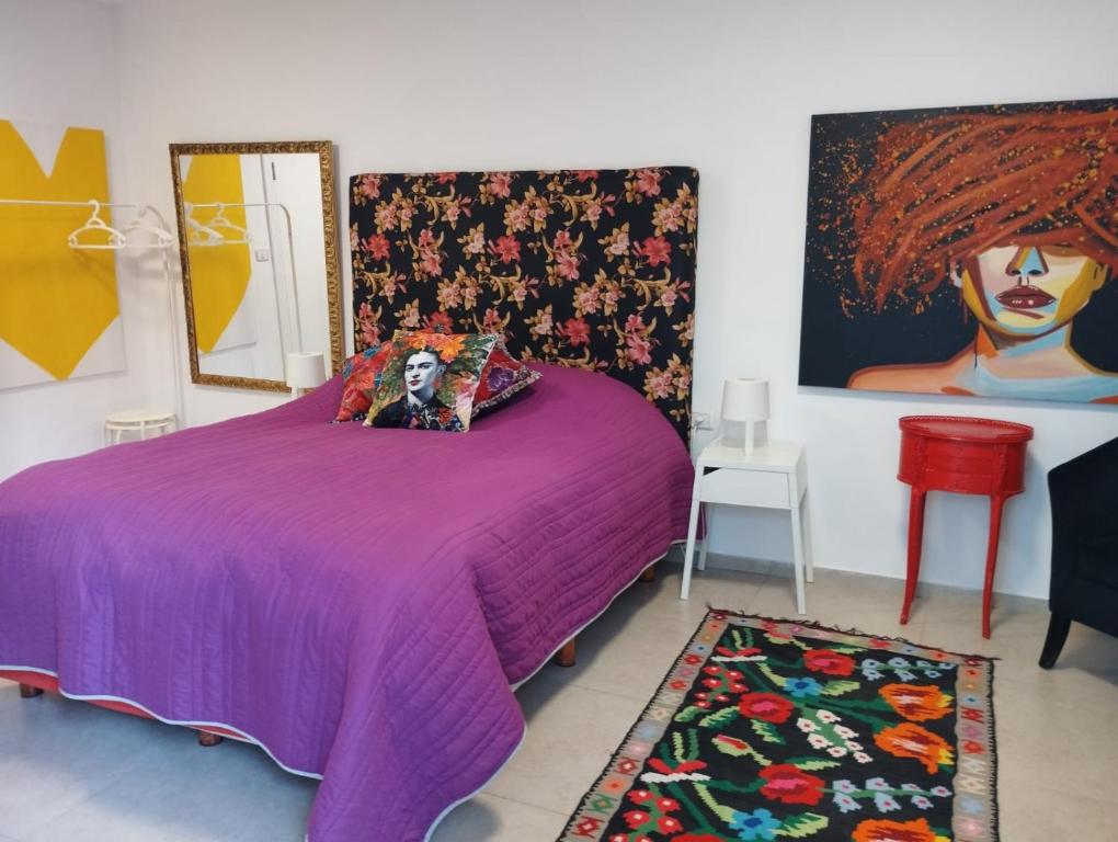 a bedroom with a purple bed with a painting on the wall at Mi Casa Tu Casa - Dead Sea in Vered Yeriho