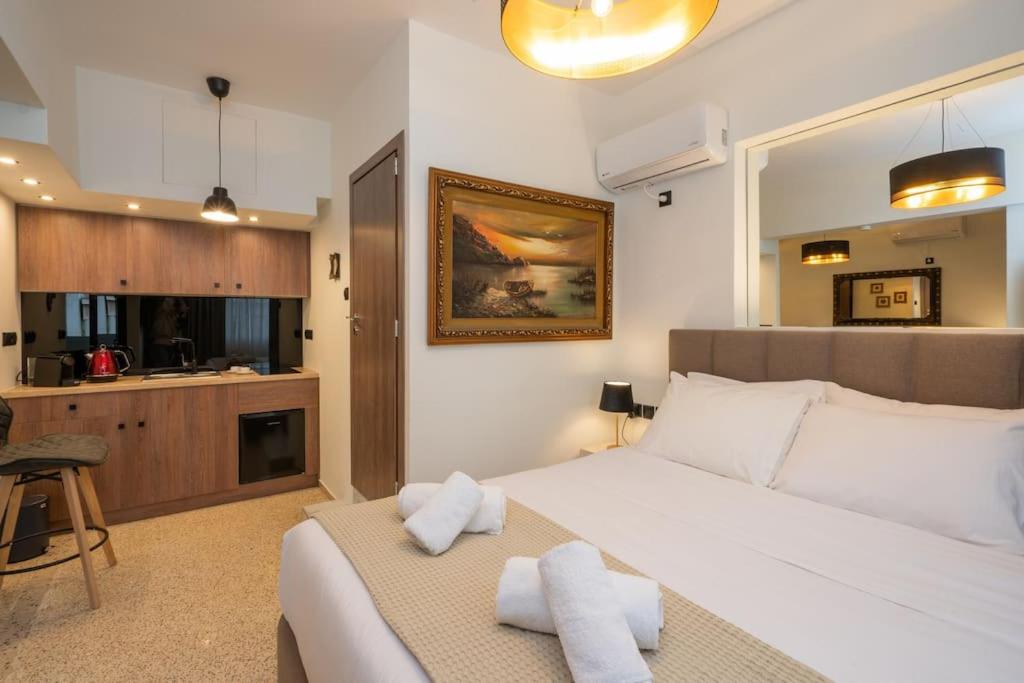 a bedroom with a large white bed and a kitchen at Dema Luxury Suites - Perikleous E6 in Athens