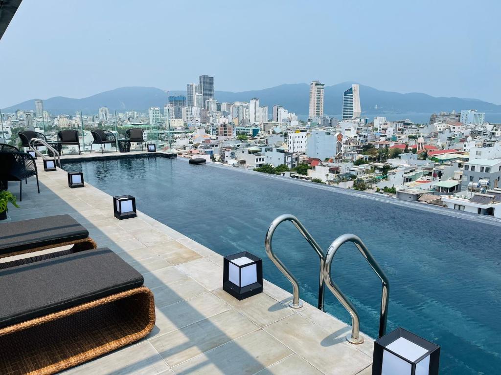A rooftop infinity pool overlooks Danang's dense cityscape and surrounding mountains.