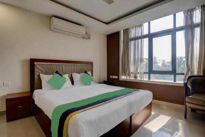 a bedroom with a large bed with a large window at Rotano Glitz Inn - Glitz Inn Calicut in Kozhikode