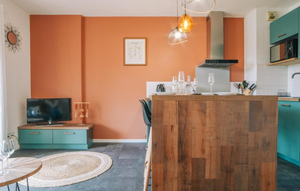 a kitchen with orange walls and a table with a television at T2 moderne avec terrasse à 900m des plages in Guéthary