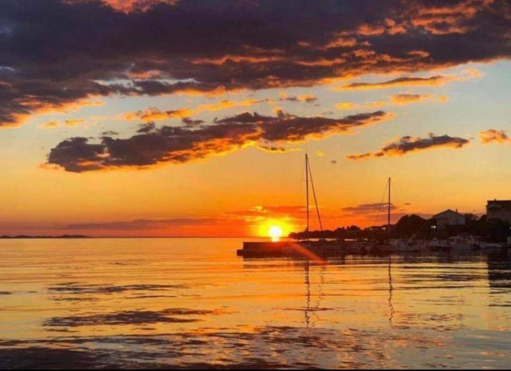 a sunset over a body of water with a boat at Apartments Marina in Petrcane