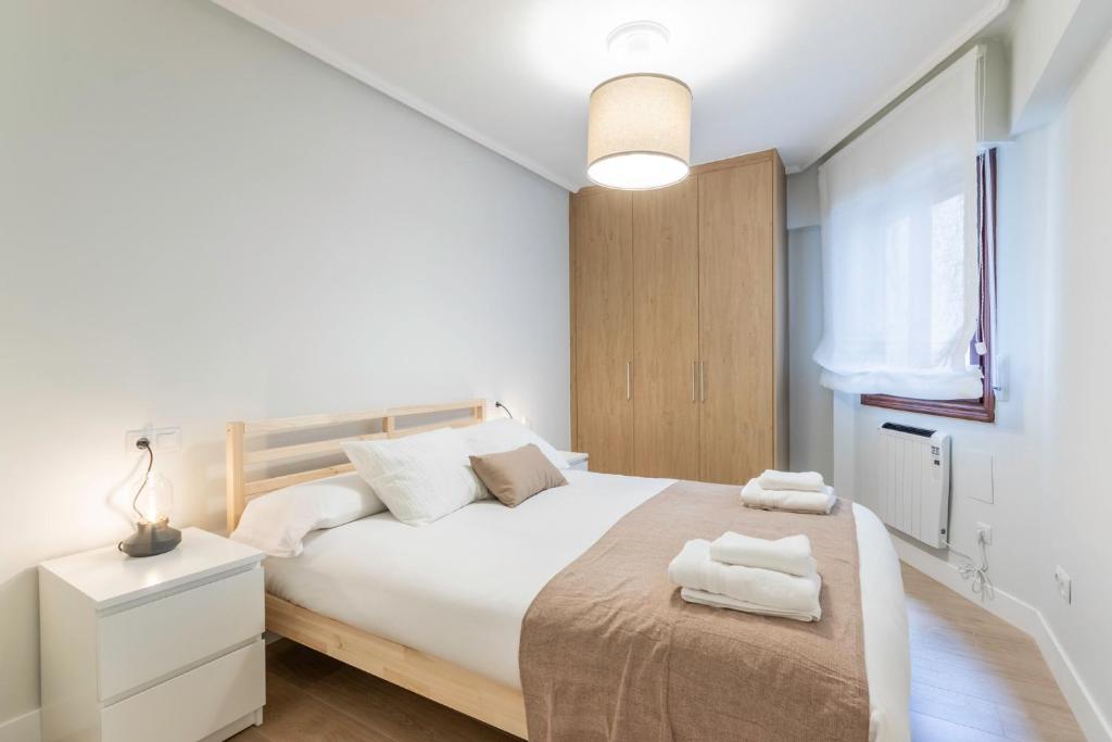 um quarto branco com uma cama grande e toalhas em Portu Cozy by Aston Rentals em Portugalete