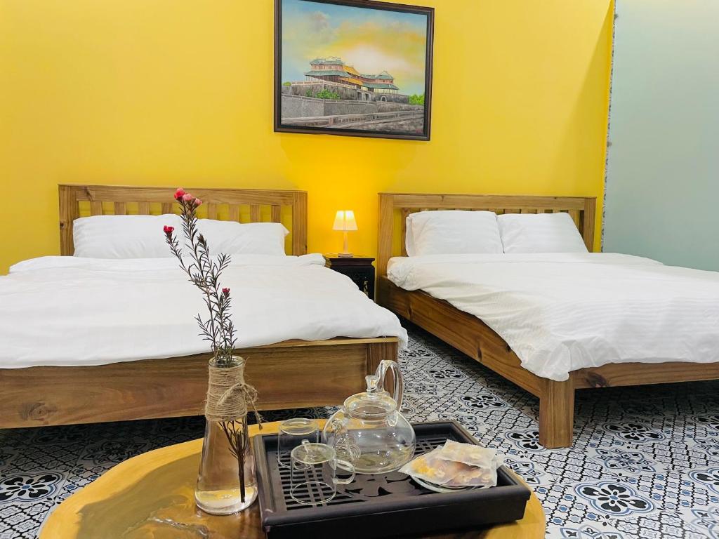 a hotel room with two beds and a table with a tray at Trú Homestay Huế in Thôn Dương Xuân Hạ