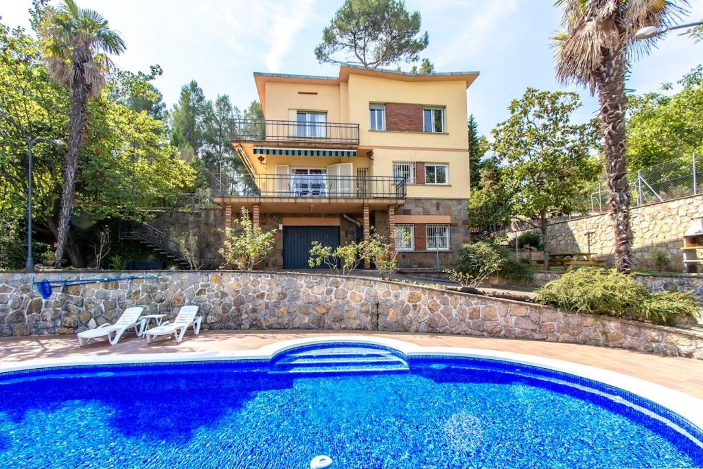 a villa with a swimming pool in front of a house at Catalunya Casas Elegant Mountain Villa just 30km to Barcelona in Corbera de Llobregat