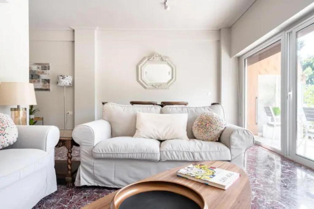 a living room with a white couch and a table at Flisvos Marina refurbished apartment in Athens