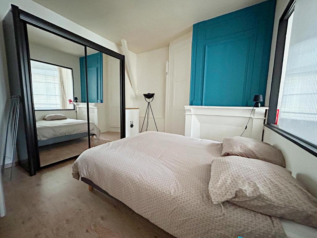a bedroom with a bed with blue walls and a mirror at L&#39;appartement du Centre in Chalons en Champagne