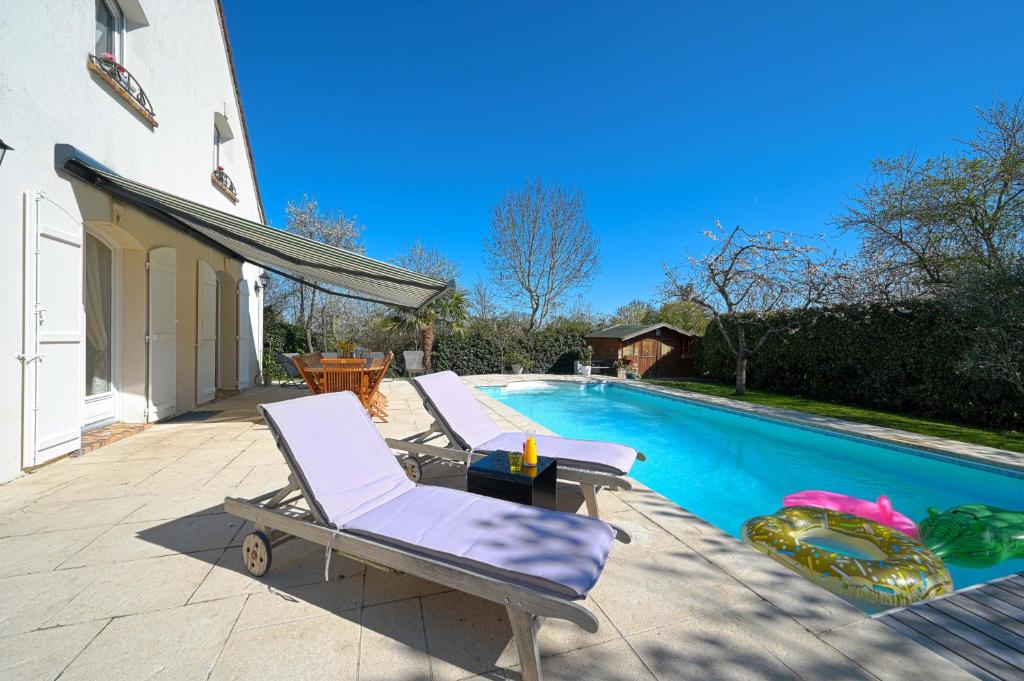 a swimming pool with two lounge chairs next to it at Albert's place idéal pour JO Paris 2024 in Médan