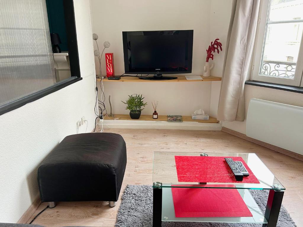 a living room with a tv and a glass table at L&#39;appartement du Centre in Chalons en Champagne