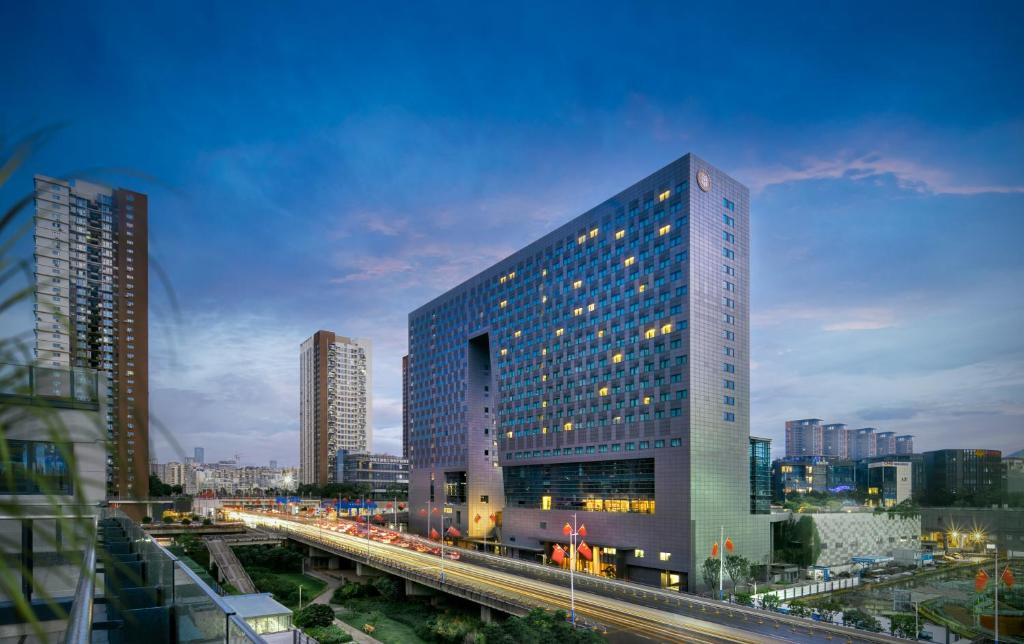 un edificio alto en una ciudad con un tren en Genpla Hotel, Shenzhen Qianhai en Shenzhen