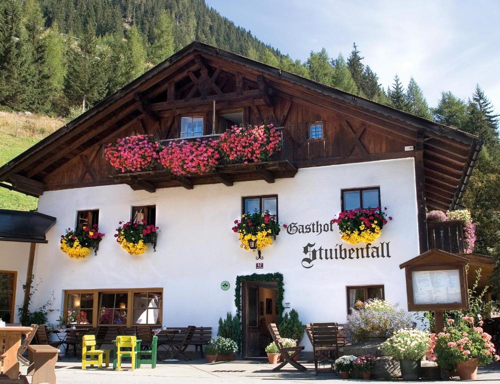 ein Gebäude in den Bergen mit Blumen darauf in der Unterkunft Hotel Gasthof Stuibenfall in Niederthai