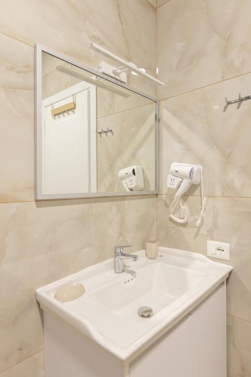 un bagno con un lavandino bianco e uno specchio di Palm Side Hotel a Vlorë