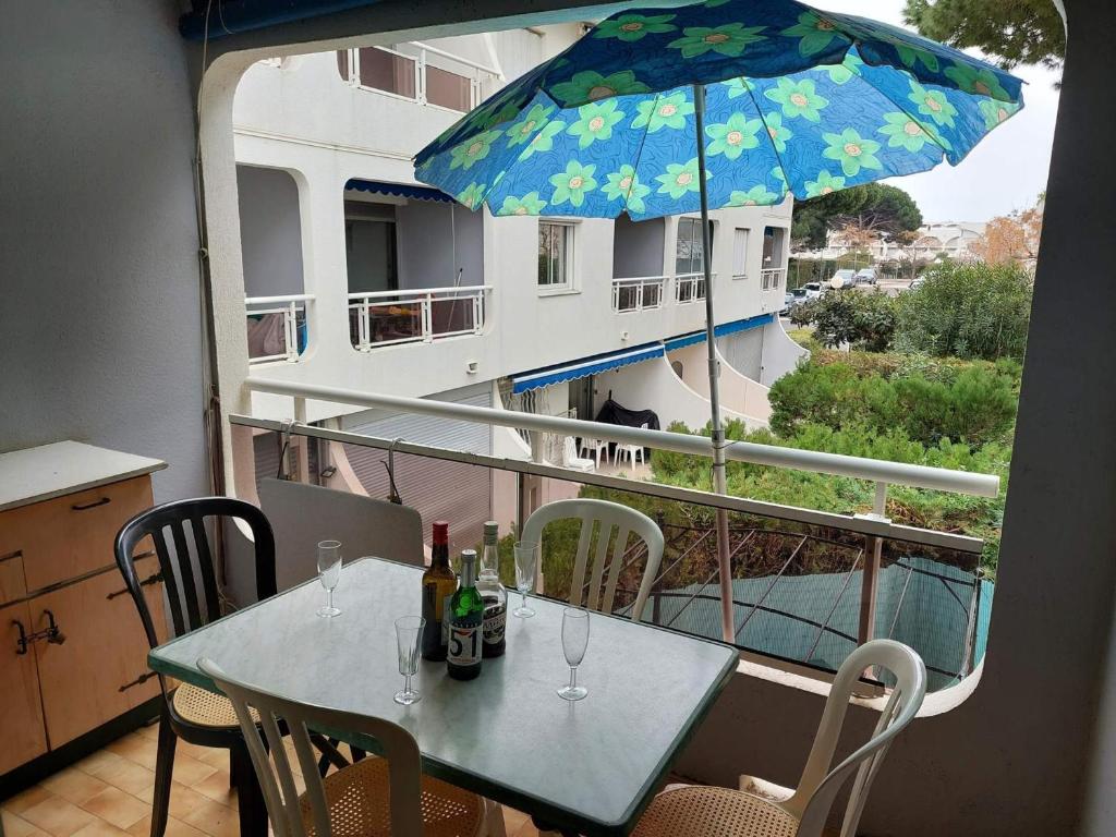 - une table avec des bouteilles de vin et un parasol sur le balcon dans l'établissement Studio cosy à La Grande-Motte avec parking privé - FR-1-716-41, à La Grande Motte