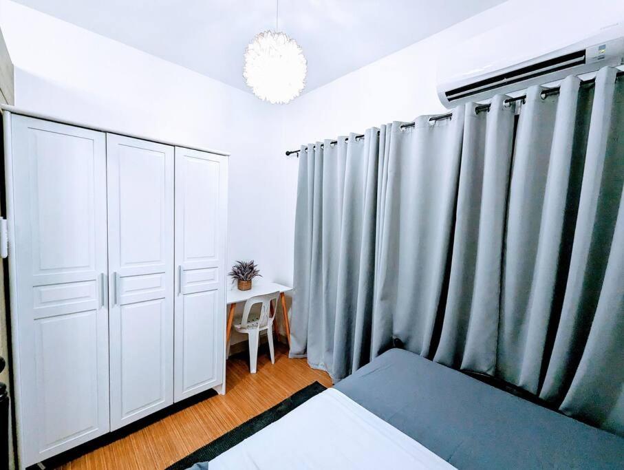 a bedroom with white furniture and gray curtains at Love@Grace Residences near BGC. in Manila