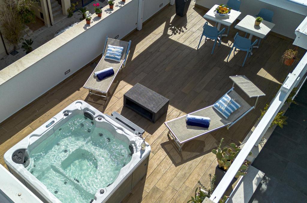 a hot tub on a balcony with a table and chairs at Acquarò Suite Jacuzzi in San Vito lo Capo