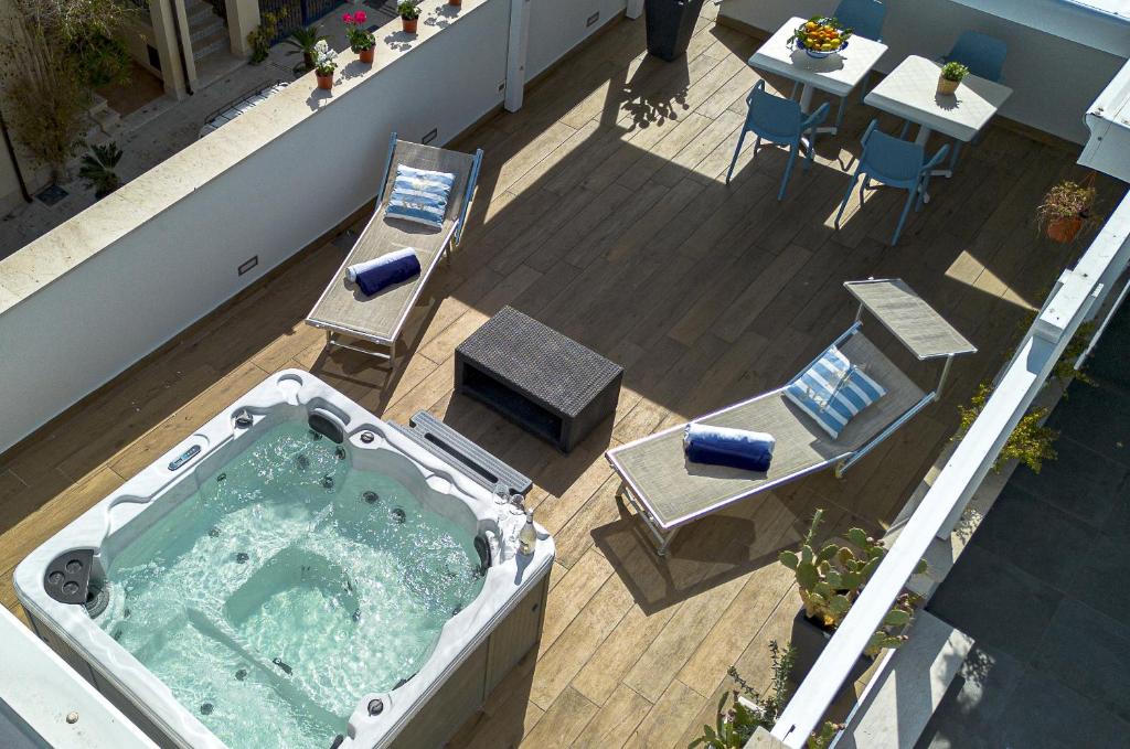 a hot tub on a balcony with a table and chairs at Acquarò Suite in San Vito lo Capo
