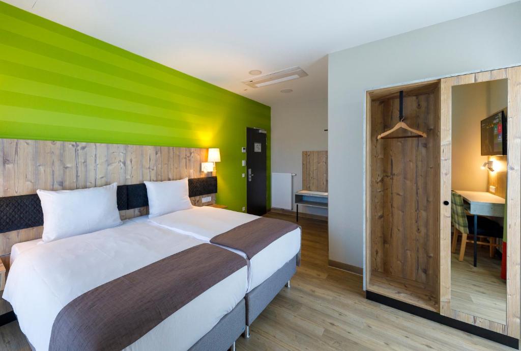パーペンブルクにあるKedi Hotel Papenburgの緑色のアクセントの壁のベッド1台が備わるベッドルーム1室