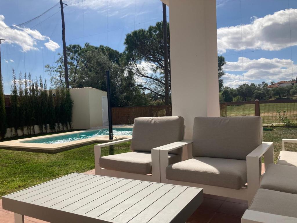 2 sillas y una mesa en un patio con piscina en Chalet Hato Verde Golf, en Guillena