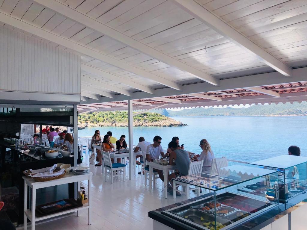 people sitting at tables in a restaurant next to the water at Narr Hotel in Kaş