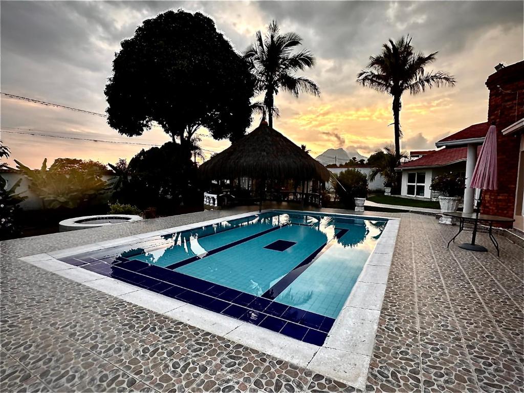 une grande piscine bleue dans une cour avec des palmiers dans l'établissement El Bongo de Chinauta, à Fusagasuga