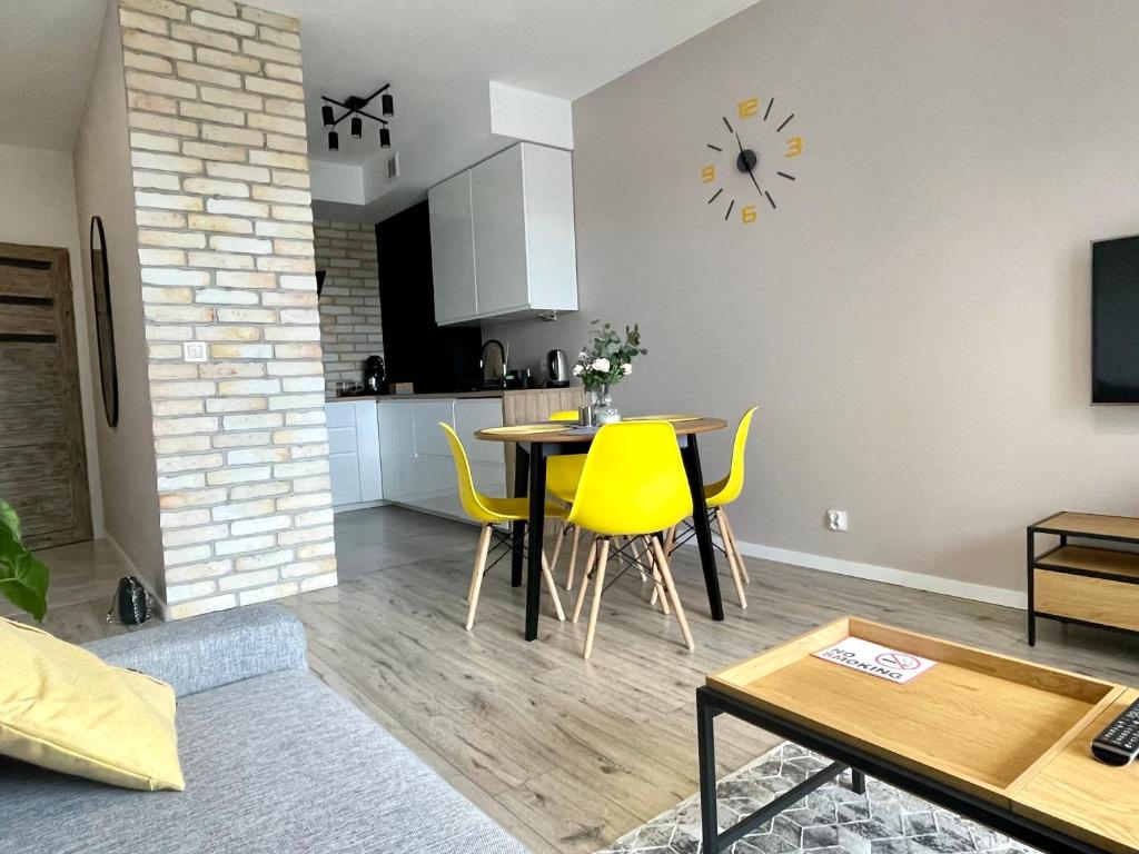 uma sala de estar com uma mesa e cadeiras amarelas em Apartments Sleep & GO Modlin Airport em Nowy Dwór Mazowiecki