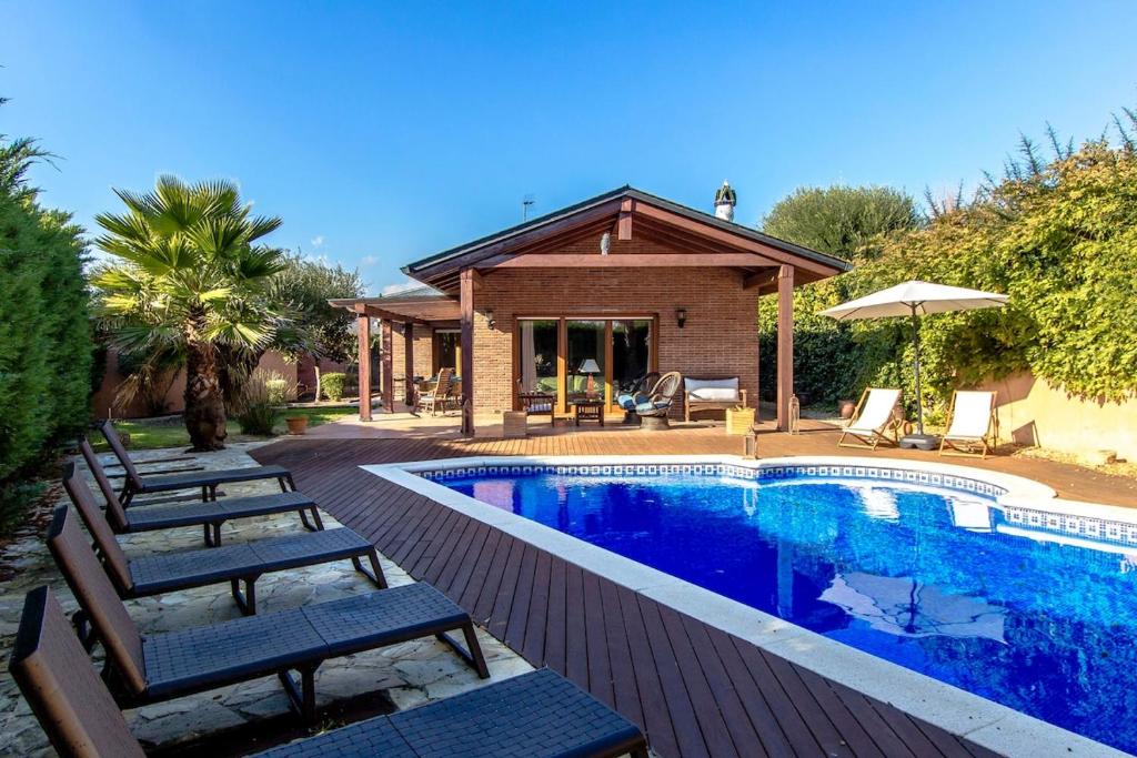a swimming pool with chairs and a house at Catalunya Casas A Costa Brava gem - only a few minutes to the beach! in Vidreres