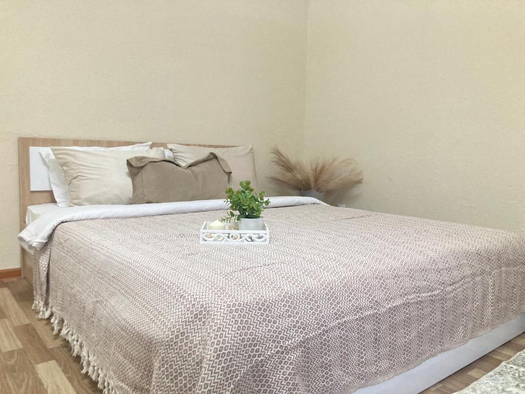 ein Bett mit einer weißen Bettdecke mit einer Pflanze darauf in der Unterkunft Уютная однушка на Сармате in Astana