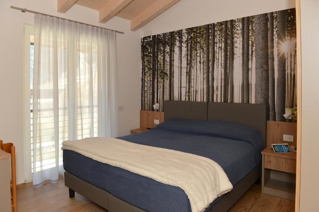 - une chambre avec un lit et des arbres sur le mur dans l'établissement Bed and Breakfast NAVIS, à Nave San Rocco