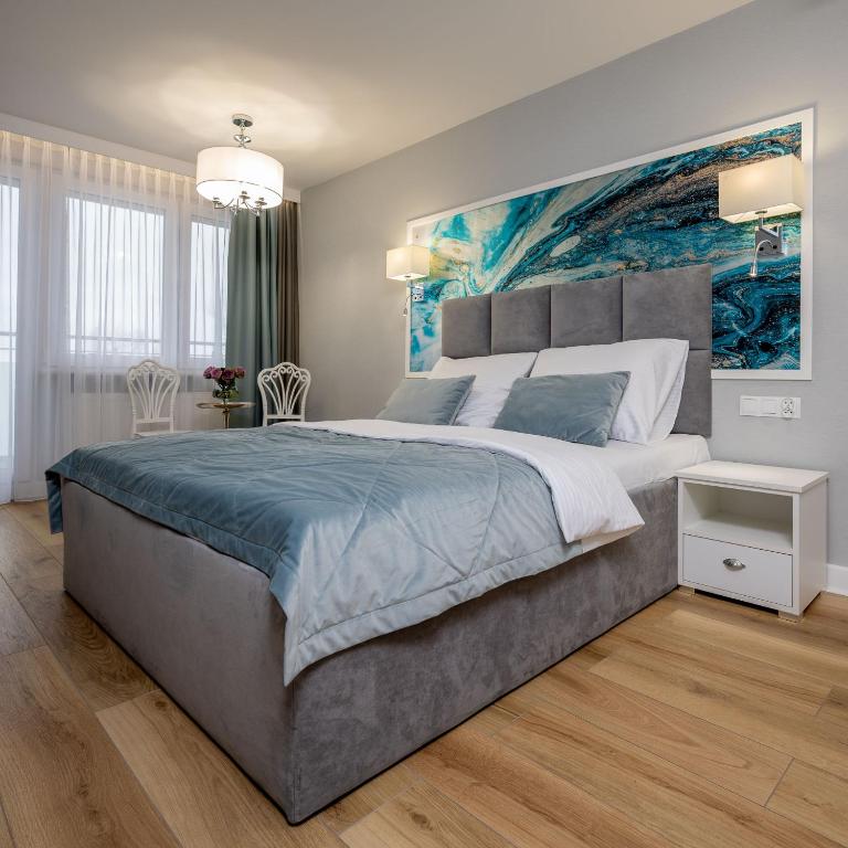 a bedroom with a large bed with a painting on the wall at Dukat Medical Spa in Dąbki