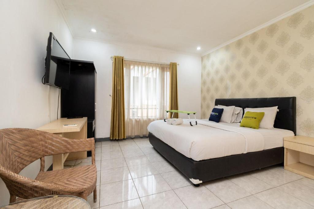 een slaapkamer met een groot bed en een stoel bij Urbanview Hotel Gunung Geulis Village by RedDoorz in Bogor