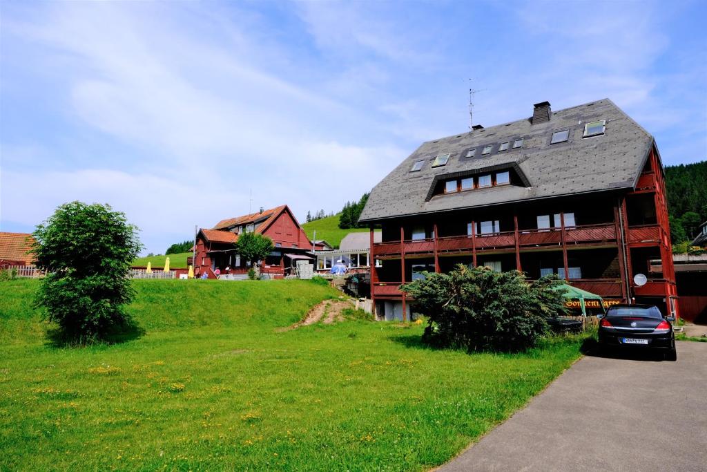 a large house on a green field with a car parked in front at Hotel Sonnenmatte Titisee B und B nahe Badeparadies in Titisee