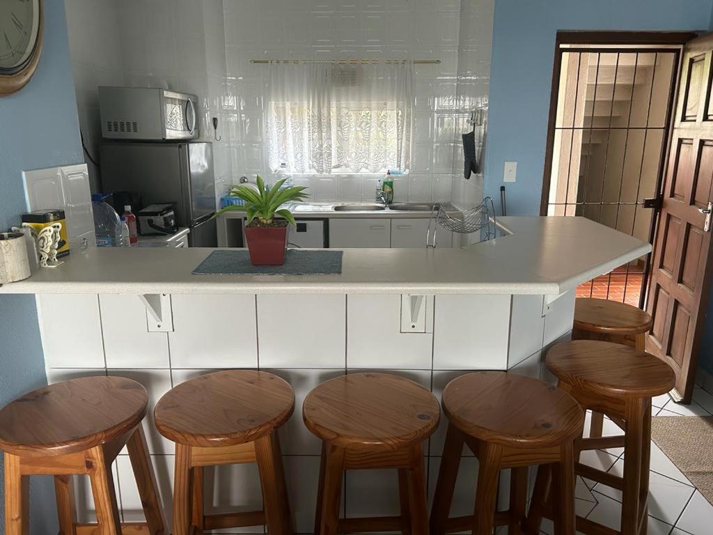 a kitchen with a island with four wooden stools at 205 Laguna lacrete in Uvongo Beach