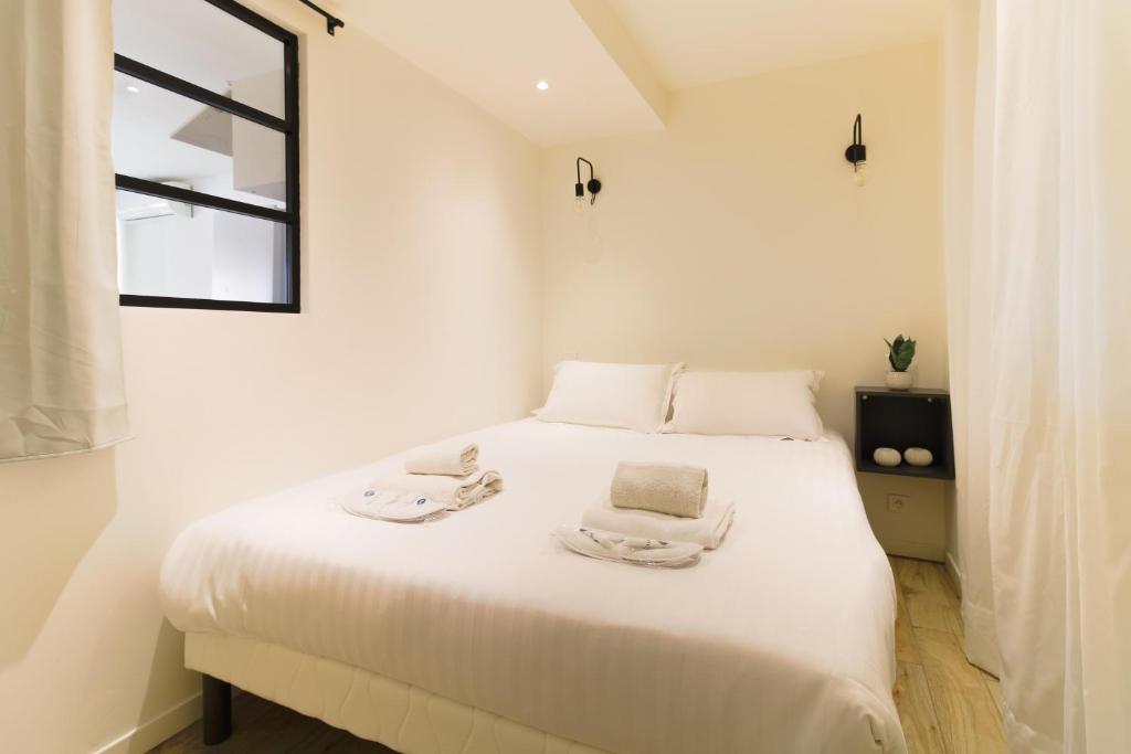 a white bedroom with a white bed with two towels on it at SELECT'SO HOME - T2 au cœur du Lavandou - Prestations de qualité - GAIA in Le Lavandou