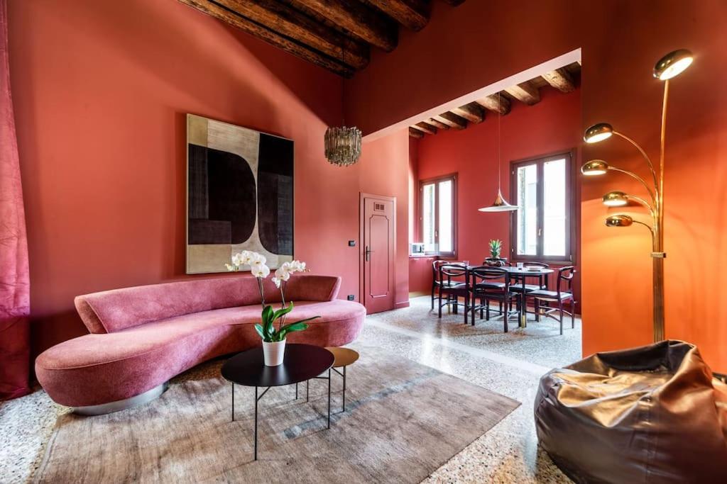 a living room with red walls and a pink couch at Cà Regina Panada - passion on the Canal in Venice