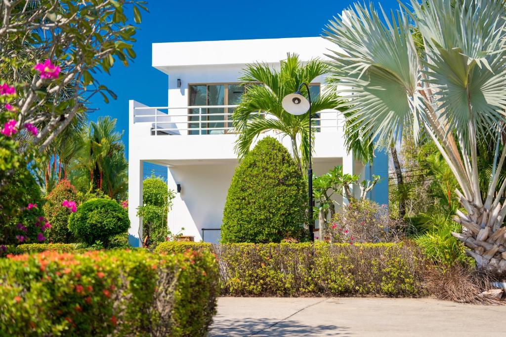 une maison blanche avec des palmiers et des fleurs dans l'établissement Le Corbusier Style Villa In Green Neighbourhood with Pool, à Mae Pim