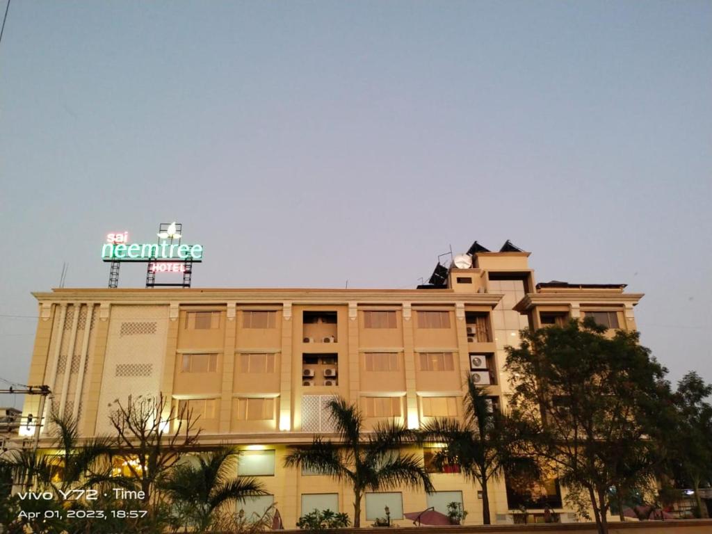 a building with a sign on the top of it at Sai Neem Tree Hotel in Shirdi