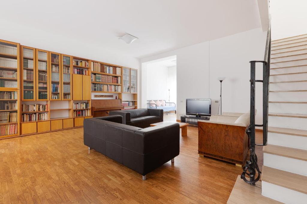 ein Wohnzimmer mit einem Sofa, einem TV und Büchern in der Unterkunft CA' STELLINI - Comoda casa indipendente con parcheggio privato in Mailand